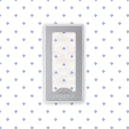 Flat lay of the Newcastle Classics Periwinkle Diamond Polka Dot bamboo muslin swaddle blanket shown with its branded packaging box in the center.