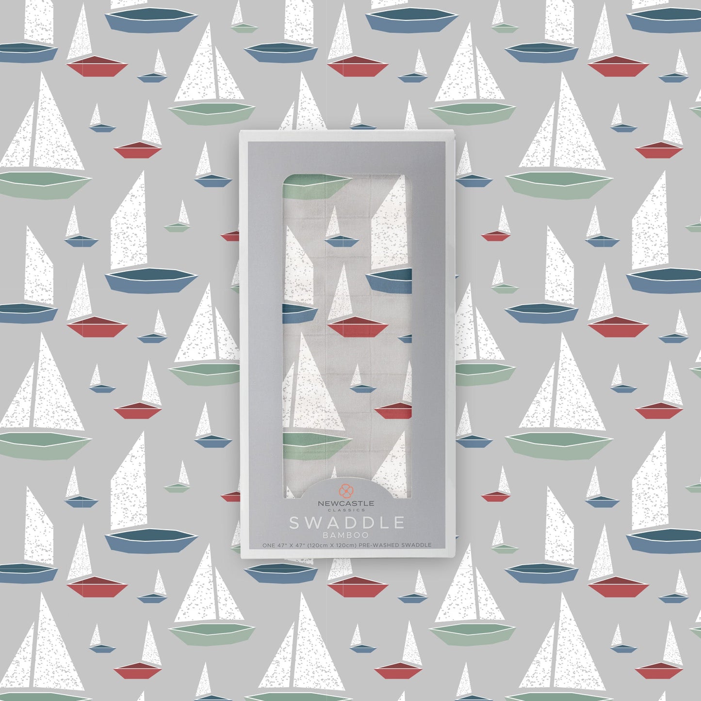 Flat lay of the Newcastle Classics Marina Sailboats bamboo muslin swaddle blanket shown with its branded grey packaging box in the center against a matching boat pattern background.