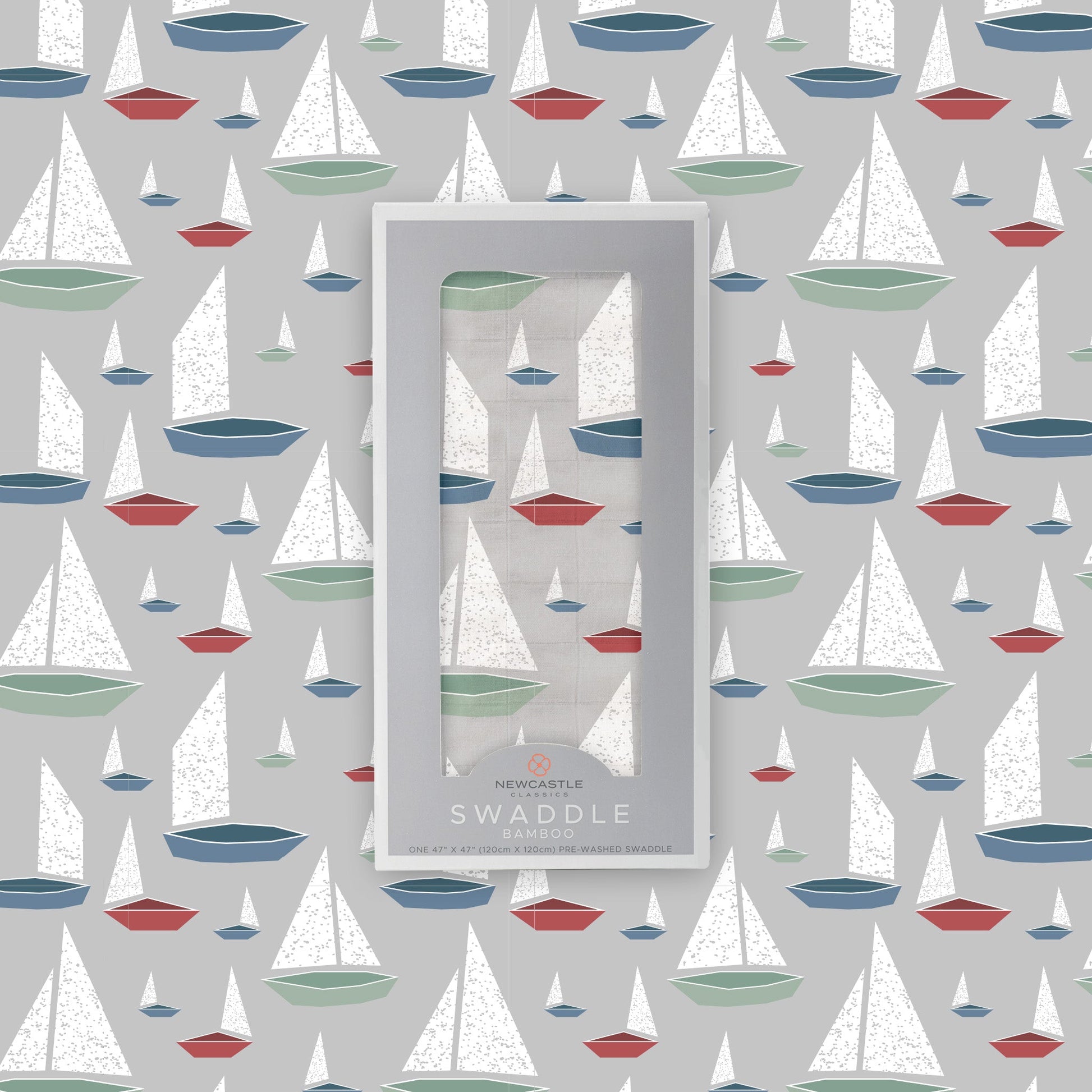 Flat lay of the Newcastle Classics Marina Sailboats bamboo muslin swaddle blanket shown with its branded grey packaging box in the center against a matching boat pattern background.