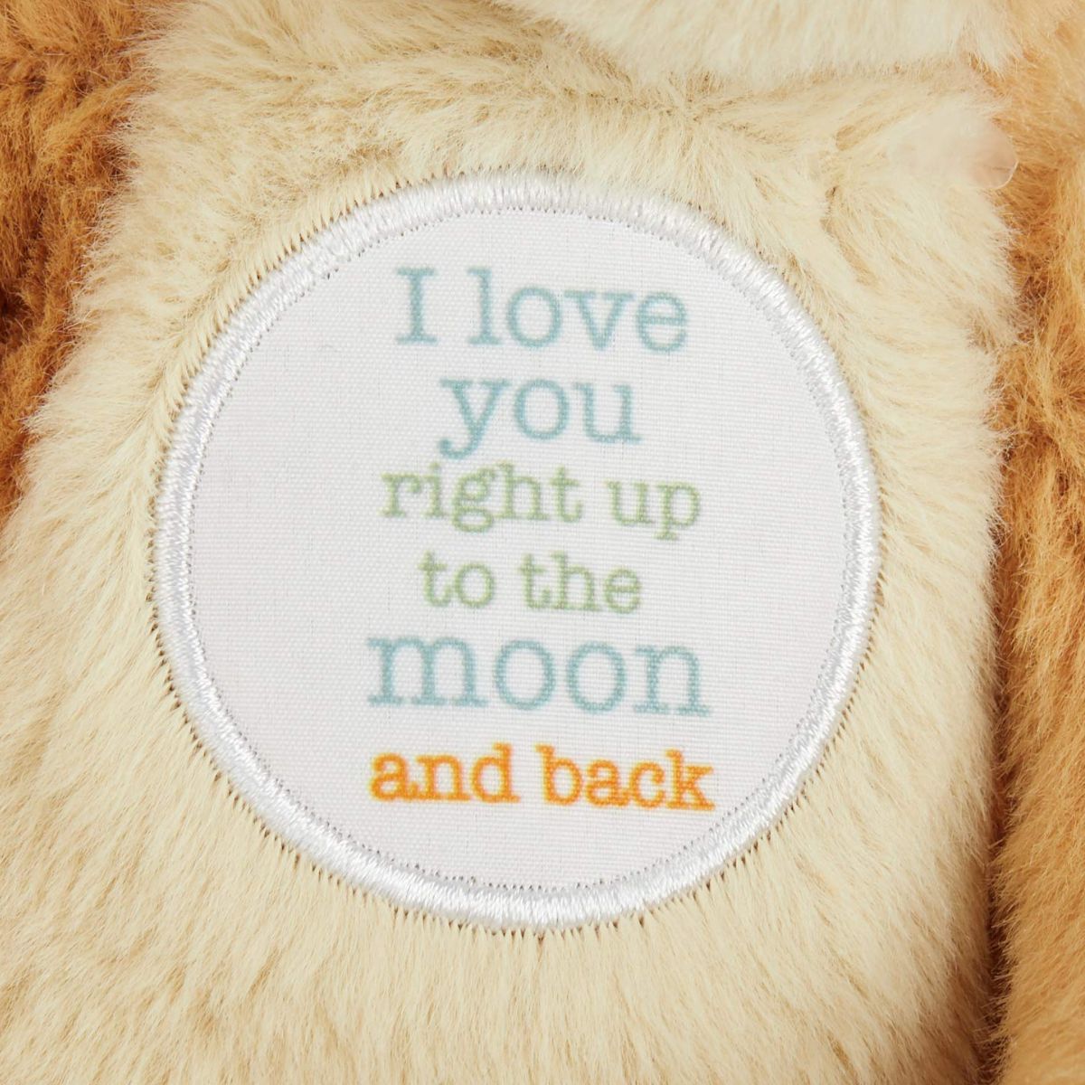 A close-up shot of the white circular patch embroidered with the text I love you right up to the moon and back.
