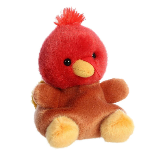 Aurora 5-inch Palm Pals Aspen Turkey plush toy sitting at an angle showing its vibrant red head, fuzzy top tuft, warm brown body, and sunny yellow beak.