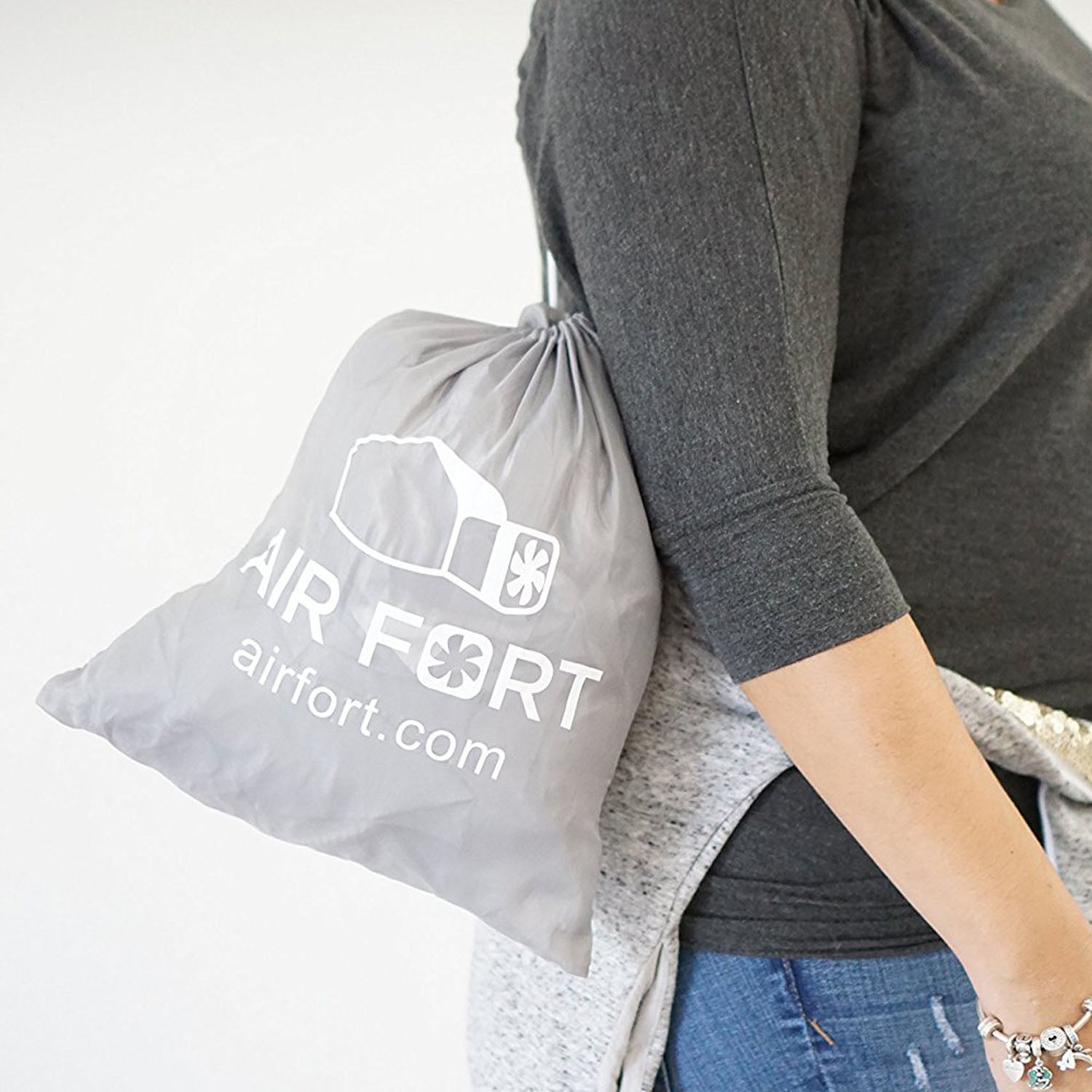 A person carrying the matching gray AirFort drawstring travel bag conveniently over their shoulder.