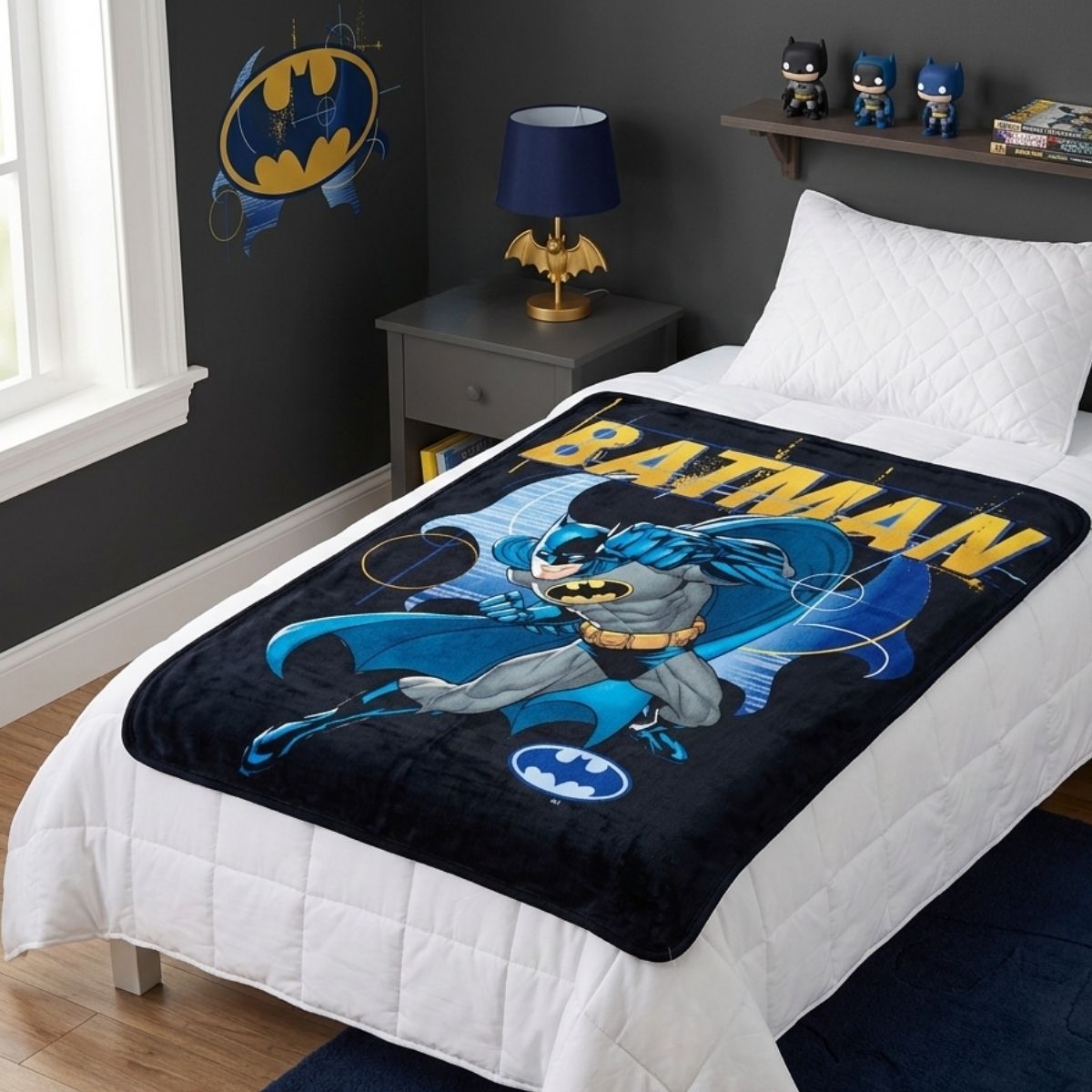 Lifestyle bedroom shot showing the Batman action blanket draped over a bed in a superhero-themed room.