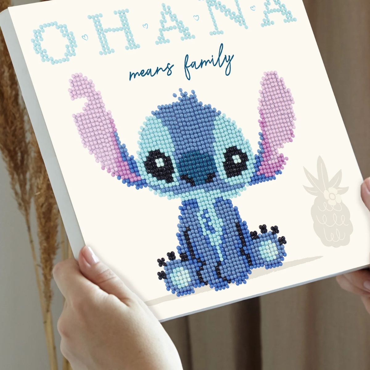 Hands holding the uncompleted 8.7 by 8.7 inch Stitch Ohana diamond painting canvas to show its size and printed design.