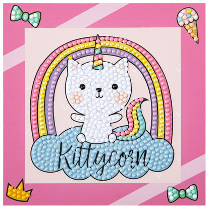Finished DIAMOND DOTZ Kittycorn diamond painting featuring a cat unicorn on a blue cloud with a rainbow on a pink background.