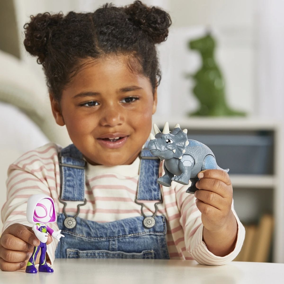 Lifestyle shot of a child playing with the Ghost-Spider and Rhino Dino toys on a table in a playroom setting.