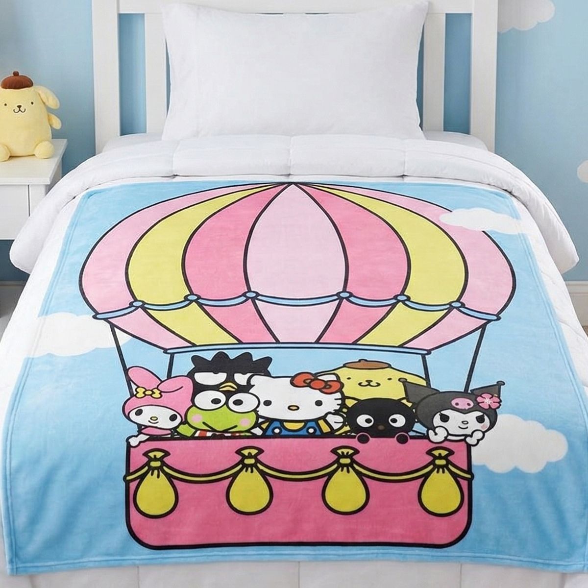 Lifestyle bedroom shot showing the Hello Kitty and Friends hot air balloon blanket draped beautifully over a bed.