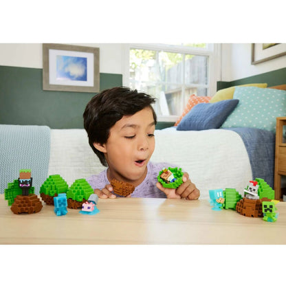 A young boy smiling while interacting and playing with multiple Minecraft Mini Mode figures and spawn eggs on a tabletop.