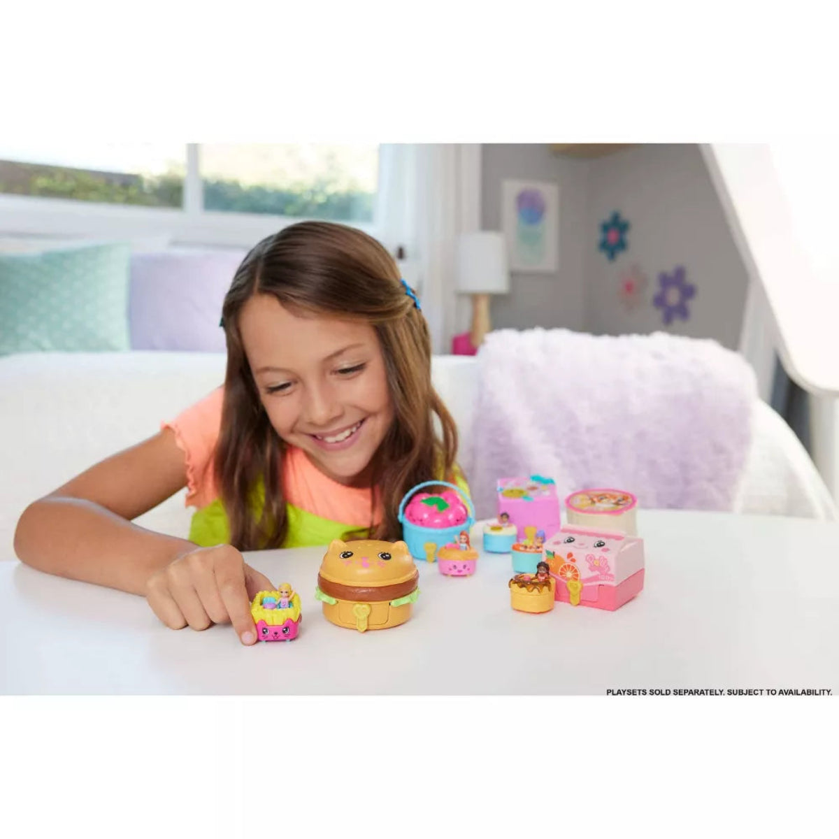 Young girl playing with toy food items on a table in a room.