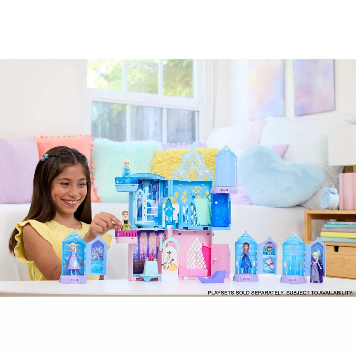 Girl playing with a toy set of colorful houses and characters in a bright room.
