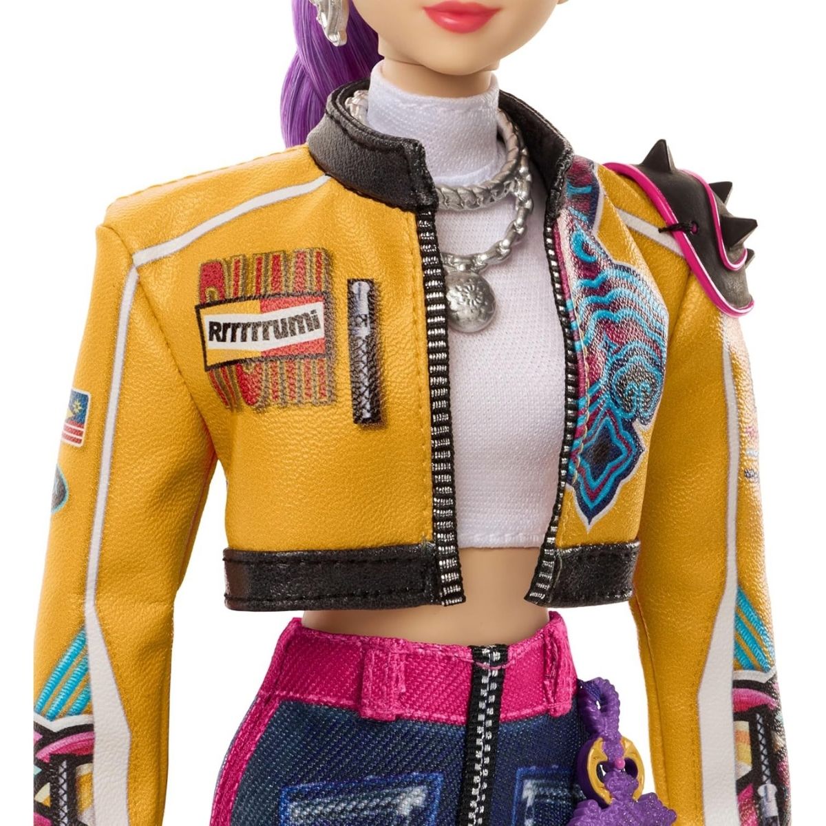 Close-up view of the K-Pop Demon Hunter Rumi doll's cropped yellow graphic jacket and layered silver chain necklaces.