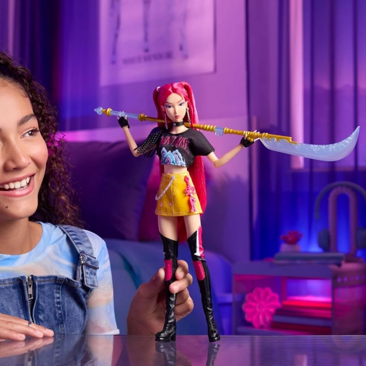 Lifestyle thumbnail showing a child playing with the Mira fashion doll in front of a purple neon room display.