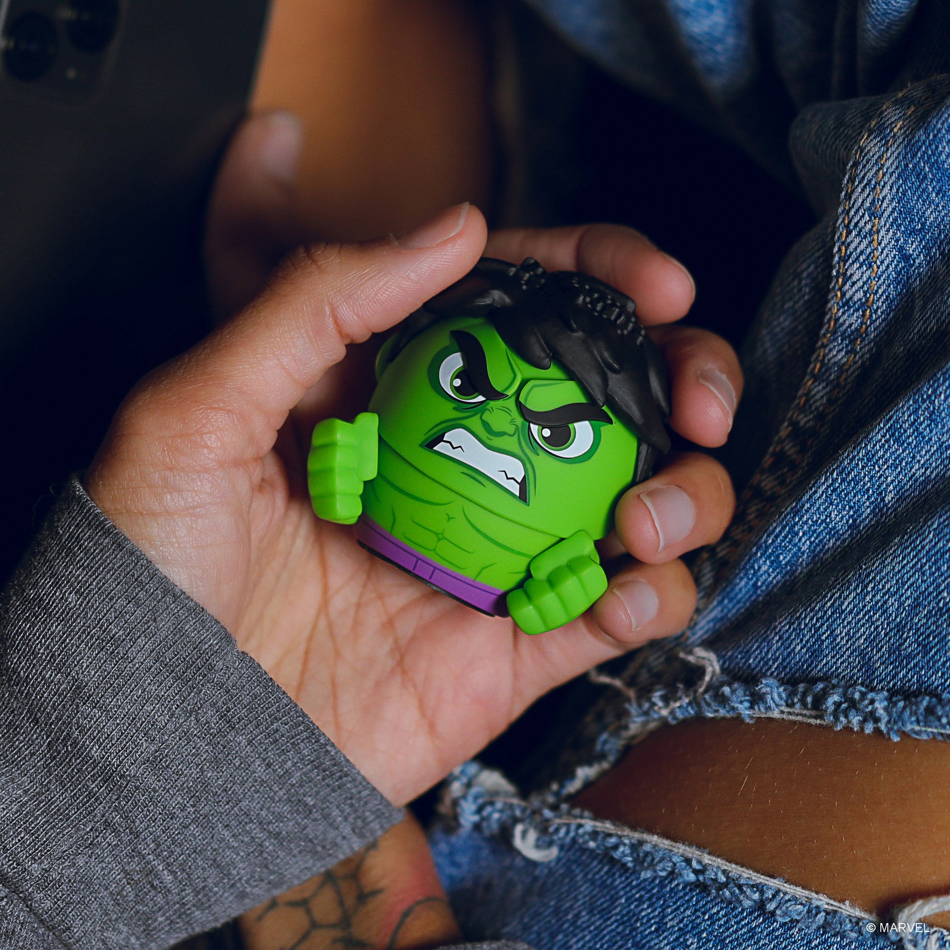 A hand holding the Bitty Boomers Hulk mini Bluetooth speaker, demonstrating its ultra-portable, 2-inch pocket-sized design.