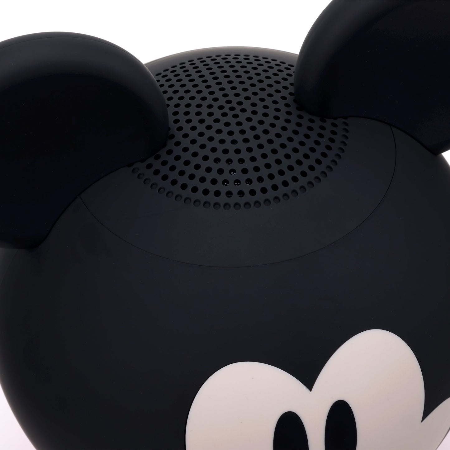 Close-up view of the top of the speaker highlighting the black ears and the top speaker grill.