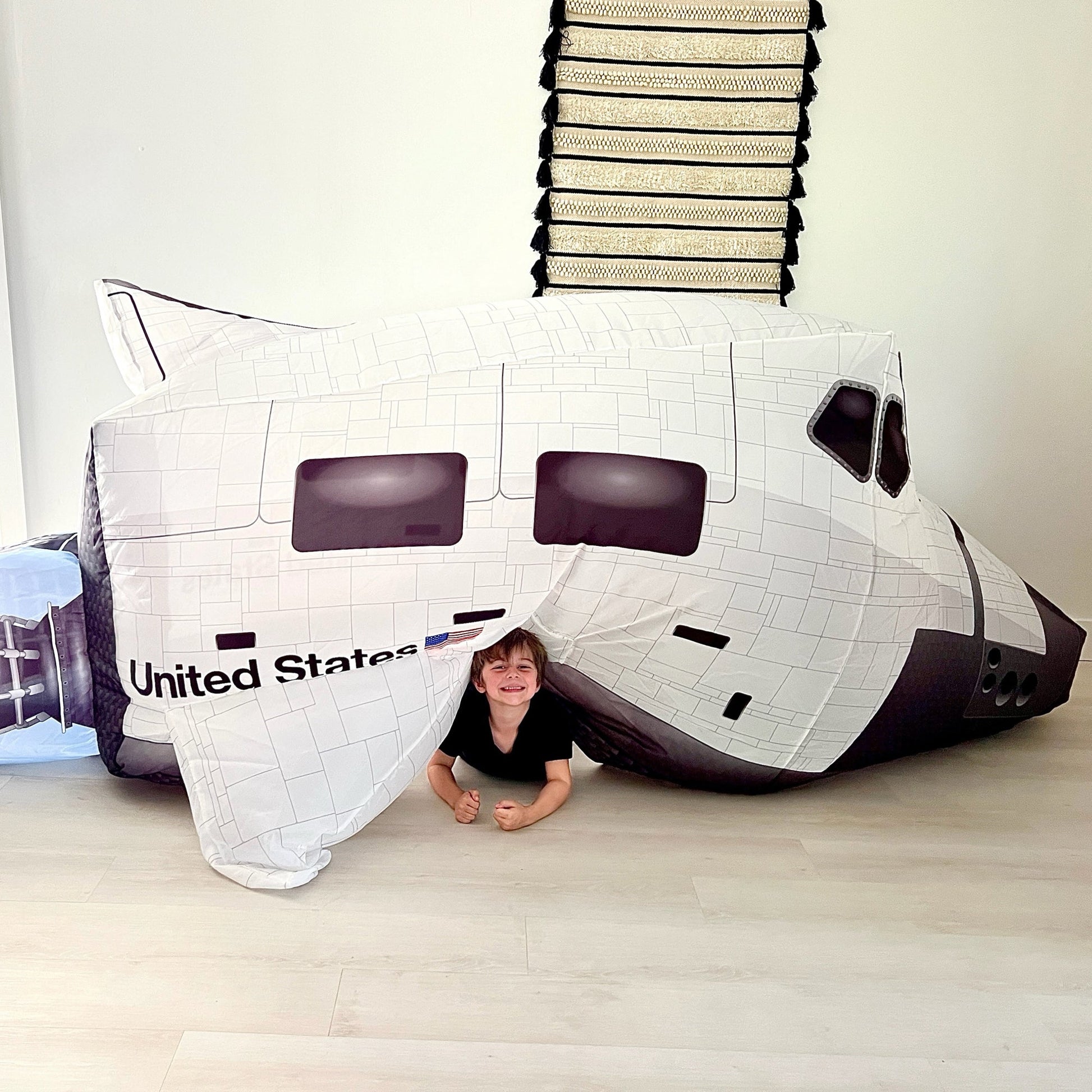 A child sitting happily underneath the side wing of the hovering Space Shuttle AirFort.