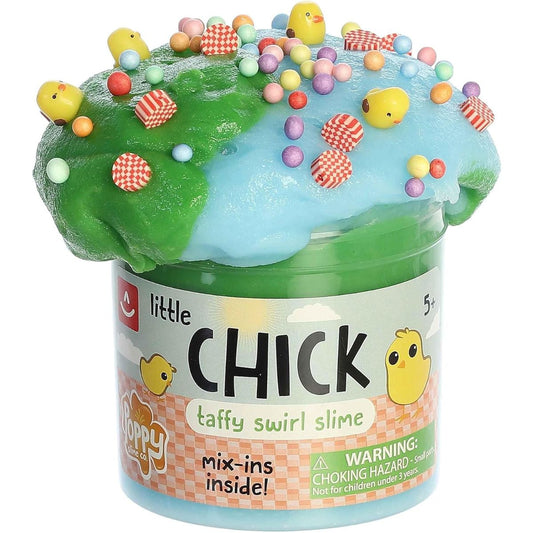 Close-up view of the green and blue swirl slime overflowing from its clear plastic jar, heavily decorated with colorful foam beads, pink squares, and yellow chick charms.