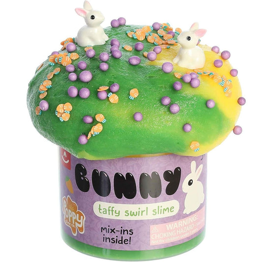 Close-up view of the green and yellow taffy slime puffed out of its container and topped with purple sprinkles, orange beads, and tiny white bunny charms.