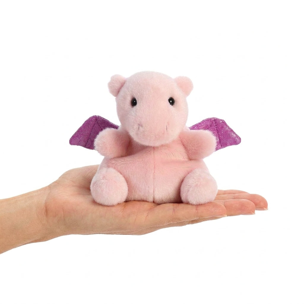 Aurora Palm Pals Aria Pink Dragon 5-inch plush held in human palm to show size.