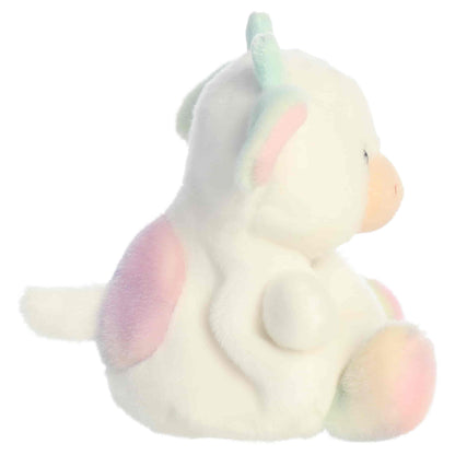 Side profile view of Aurora Palm Pals Georgia Rainbow Cow plush showing seated posture, tail, and pastel patches.