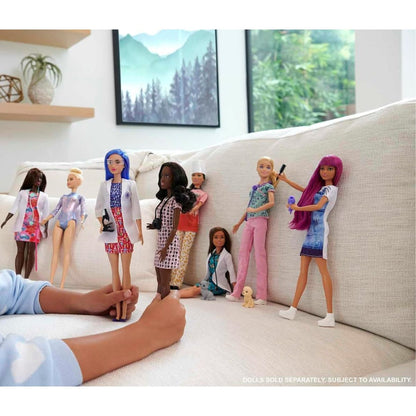 Lifestyle thumbnail showing hands playing with an assortment of Barbie career dolls on a sofa.