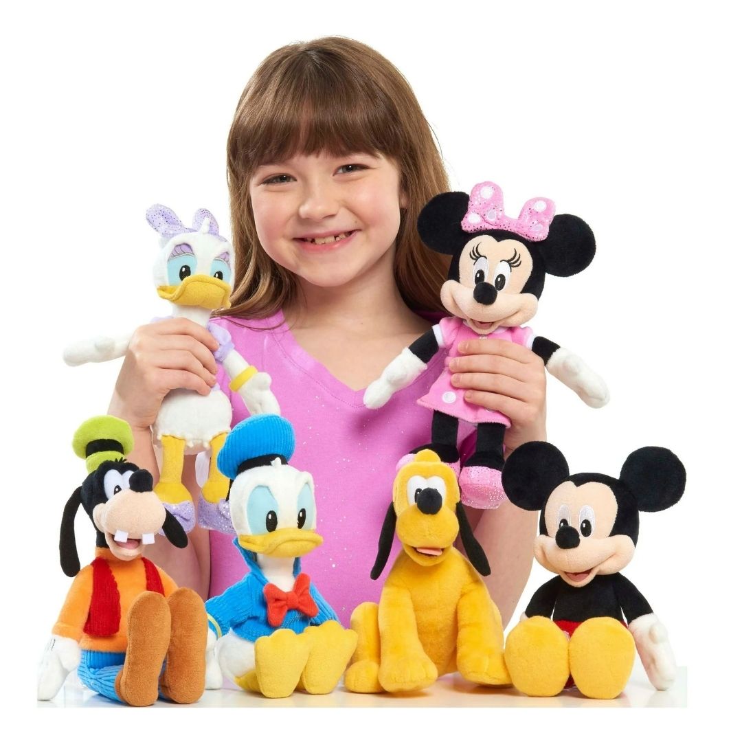 Young girl holding a collection of Disney Junior 9-inch bean plush toys including Goofy, Mickey, Minnie, Donald, Daisy, and Pluto.