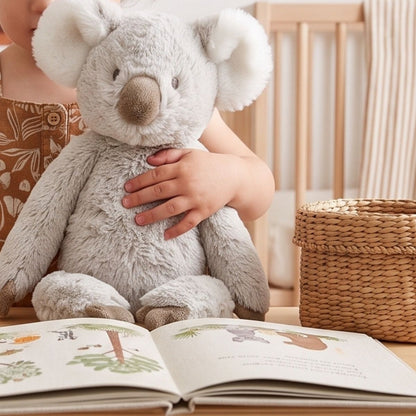 Lifestyle thumbnail showing a child hugging Happy Horse Koala Kanzo plush next to a storybook.