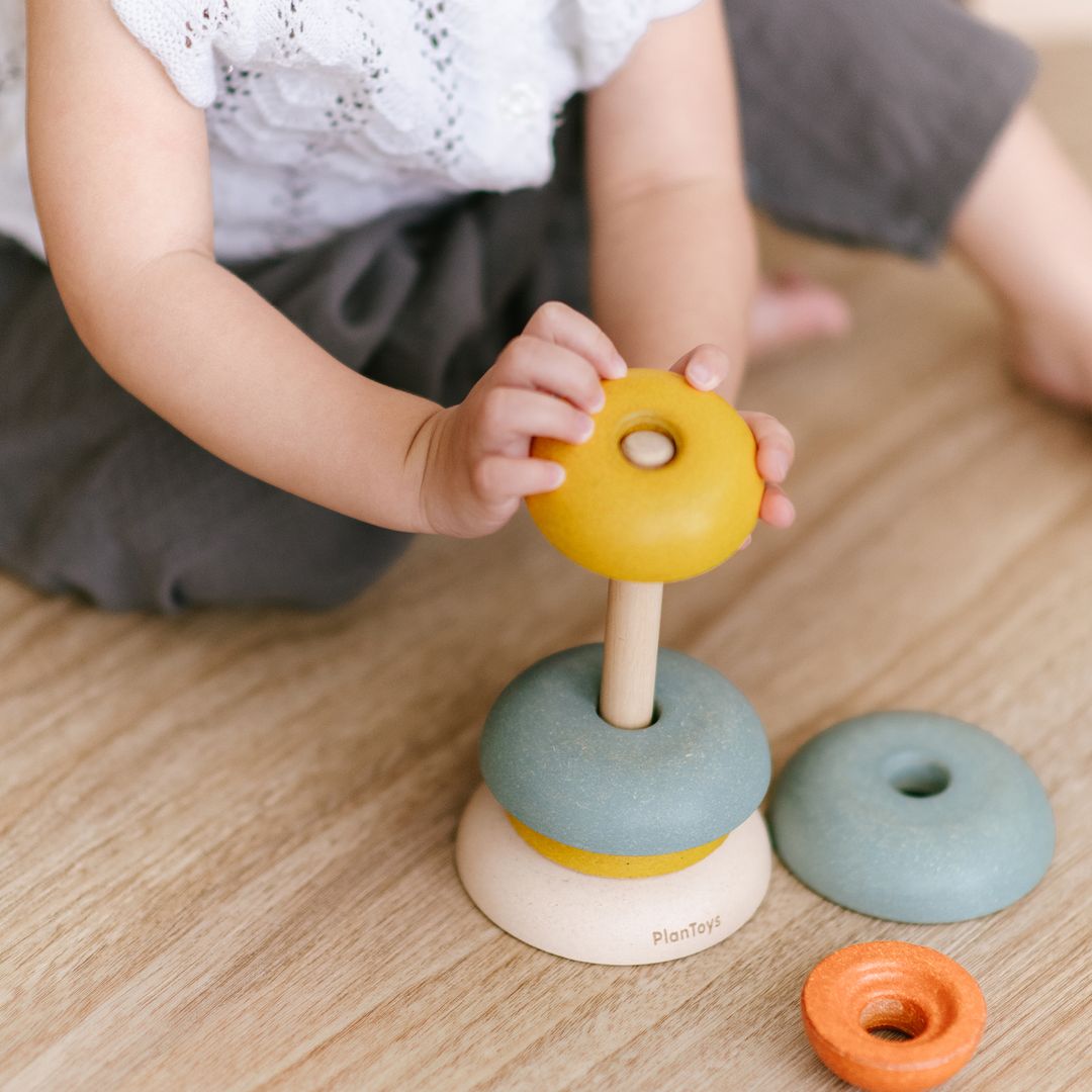 Flat lay thumbnail showing all 6 colorful wooden stacking cup pieces around the central wooden base.