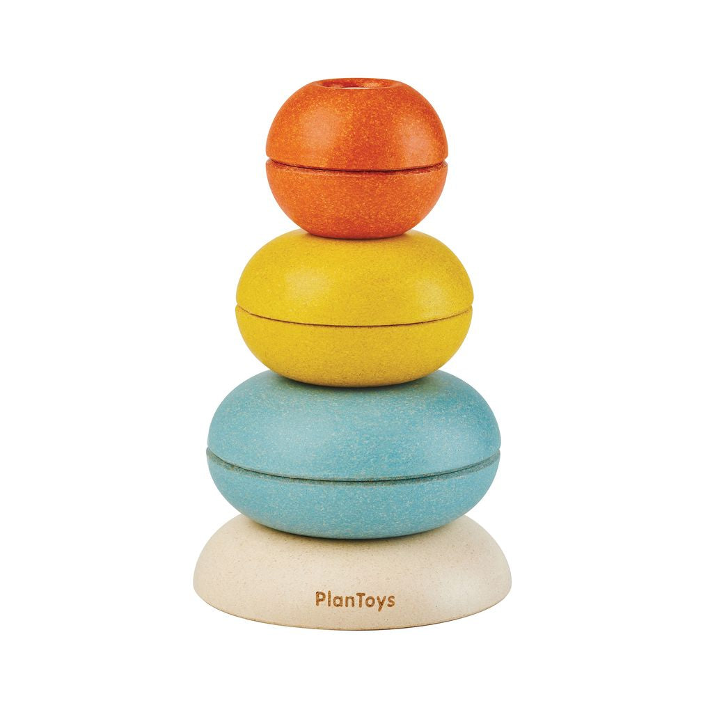 PlanToys 7-piece wooden stacking ring activity toy cups assembled into a colorful tower on a white background.