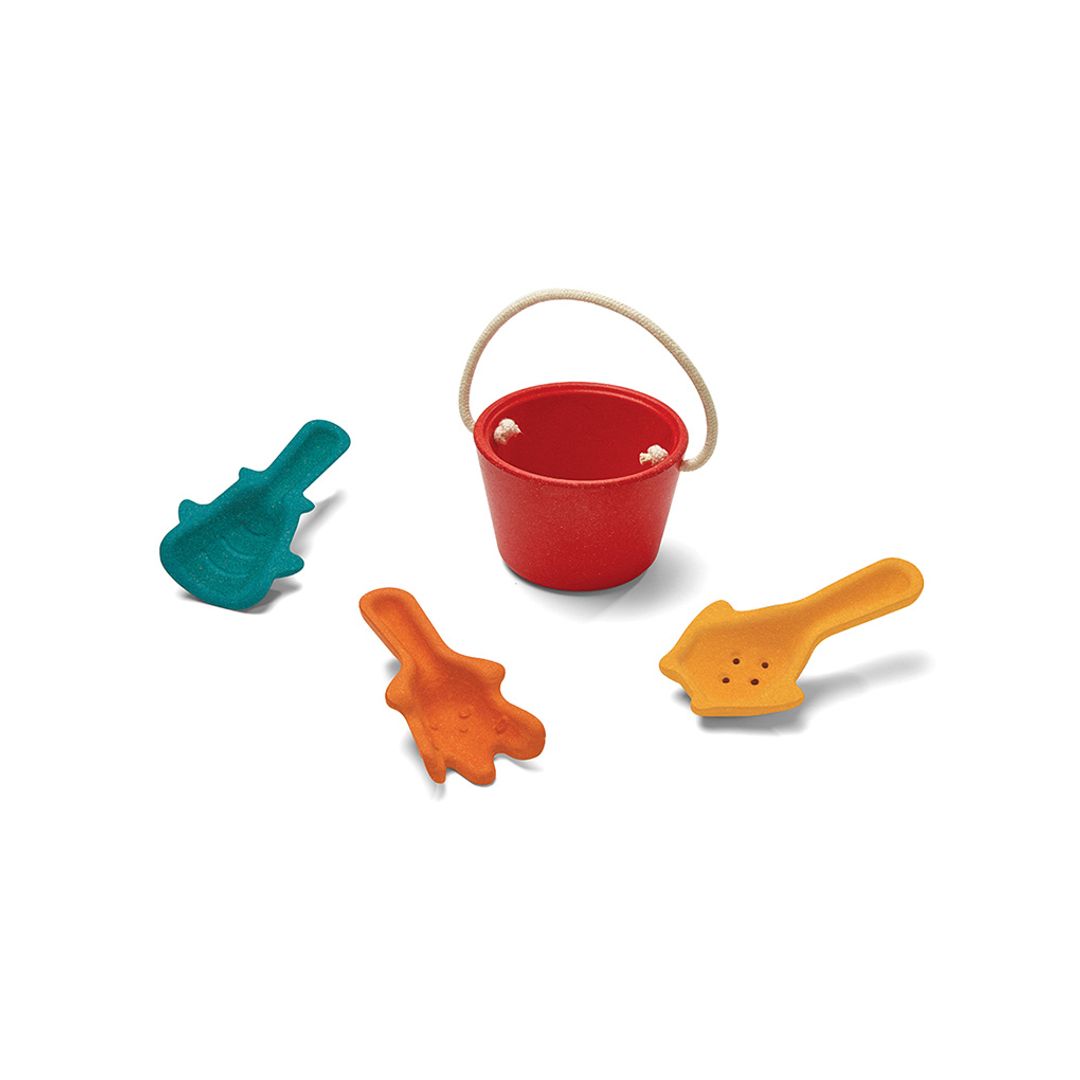 Red sand bucket with raised rope handle surrounded by teal, orange, and yellow sand tools on a white background.