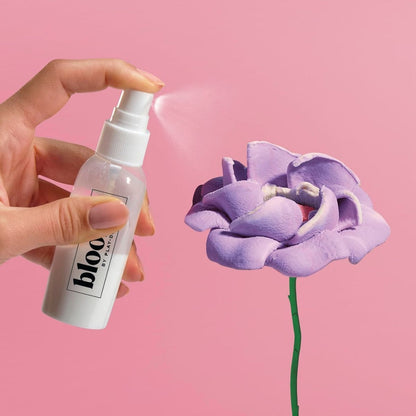 Hand spritzing preserving finishing spray onto a dried pink Play-Doh flower bloom.