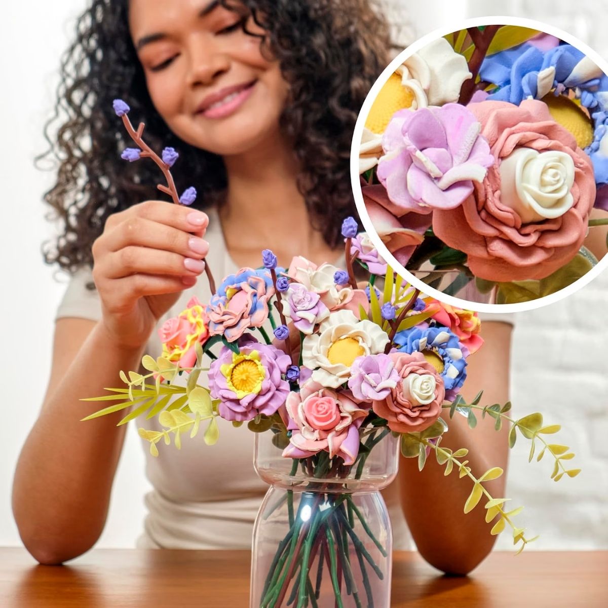 Woman placing completed Play-Doh flower blooms into a clear display vase.