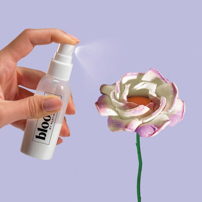 Hand spritzing preserving finishing spray onto a dried Play-Doh flower bloom.