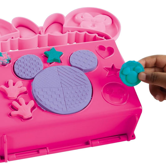 Detail thumbnail showing hands using built-in Minnie head and star shape molds on the pink bakery carrying case.