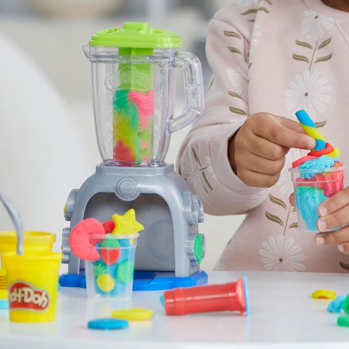Child holding a pretend play food smoothie cup filled with colorful Play-Doh toppings.