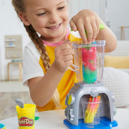 Child serving a pretend Play-Doh smoothie topped with molded fruit decorations in a clear cup.