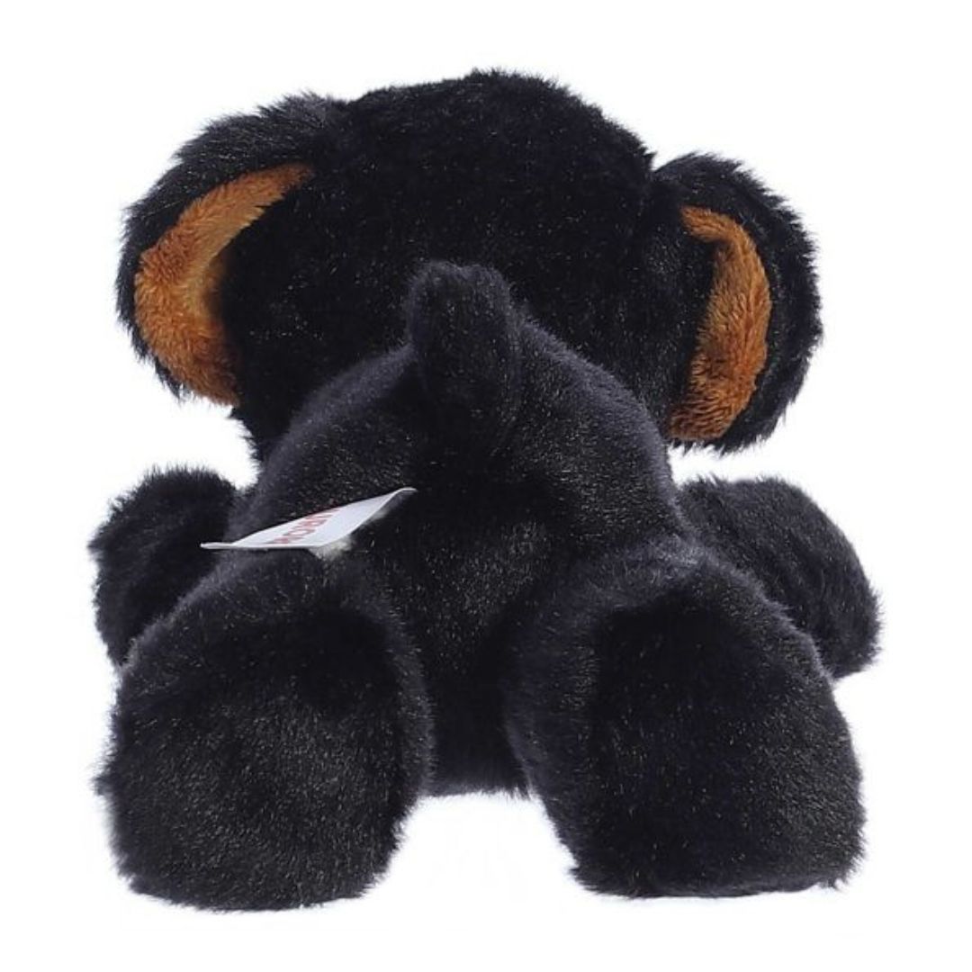 Rear view of the black Rottweiler plush showing its soft back, hind paws, and a small stubby tail.