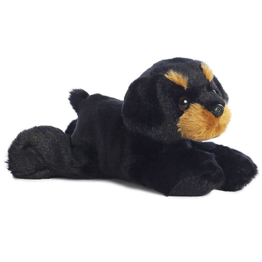 Angled side view of the Aurora Mini Flopsie Raina Rottweiler 8-inch plush resting on its belly, featuring soft black fur with tan markings.
