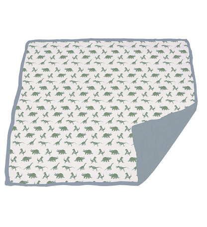 The multi-layer muslin blanket fully laid out to display the granite green dinosaur pattern with a blue fog corner fold.