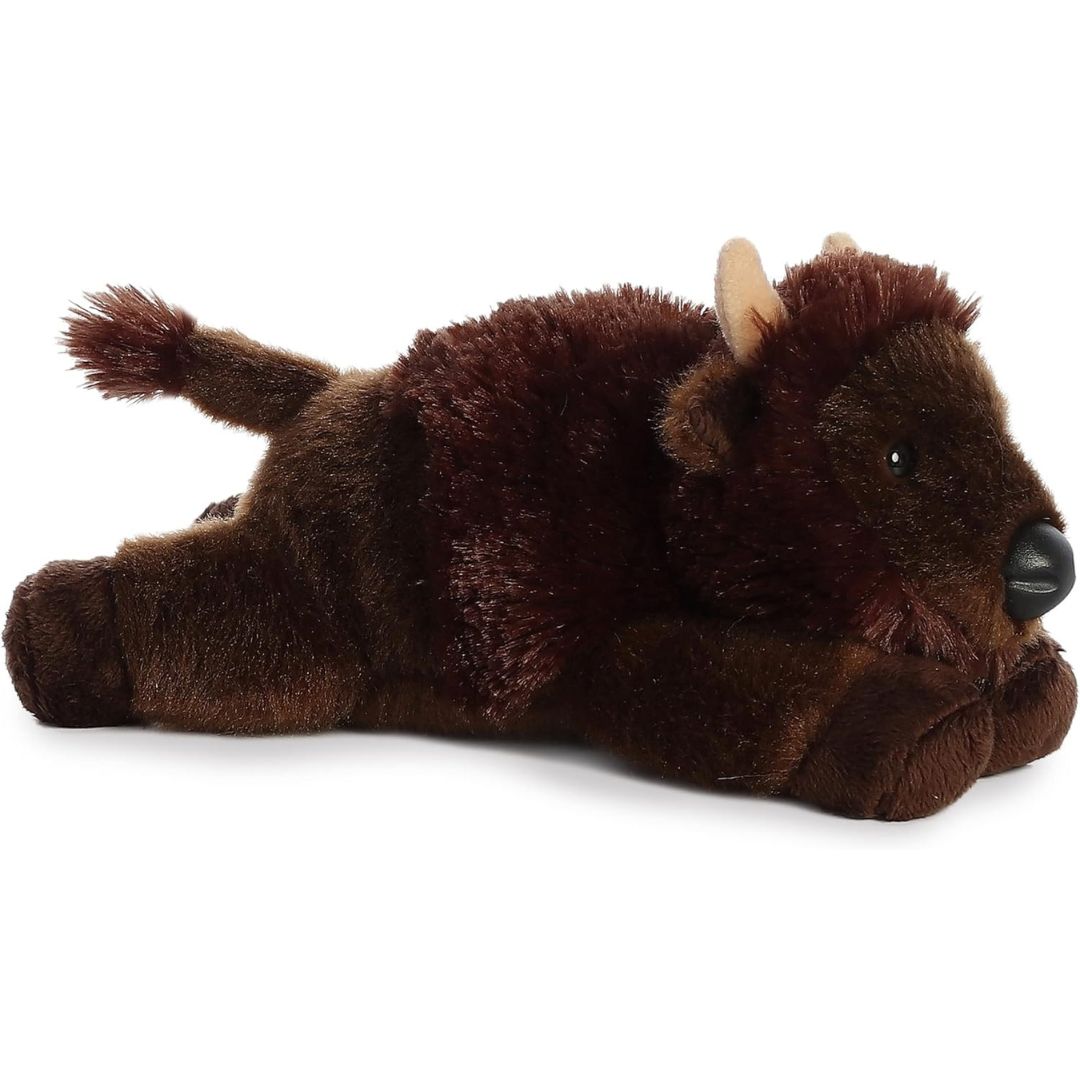 Angled side view of the Aurora Mini Flopsie Plains Buffalo 8-inch plush resting on its belly, featuring shaggy dark brown fur and small tan horns.