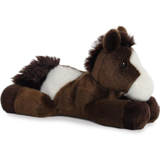 Angled side view of the Aurora Mini Flopsie Paint the Pinto Horse 8-inch plush resting on its belly, featuring dark brown and white fur.