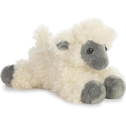Angled side profile view of the fluffy white and black plush sheep resting on its belly.