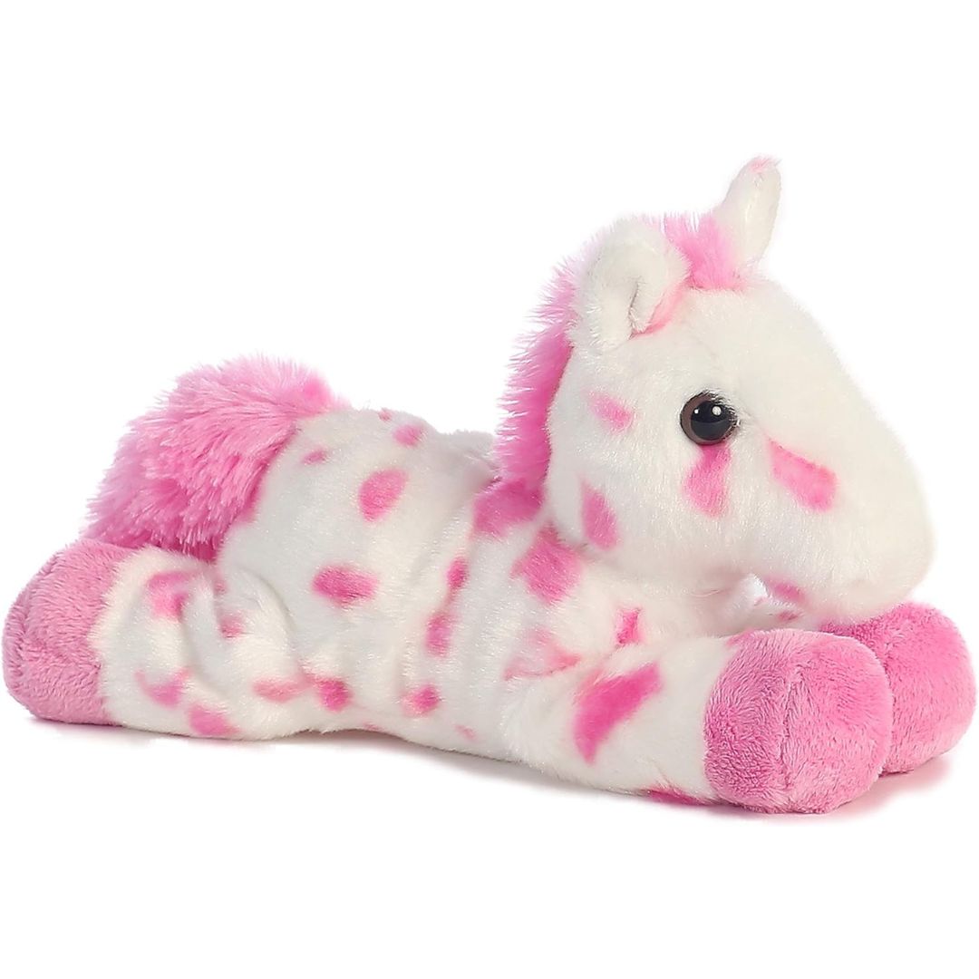 Angled side view of the Aurora Mini Flopsie Lady Appaloosa Horse 8-inch plush resting on its belly, featuring white fur with bright pink spots and a pink mane.