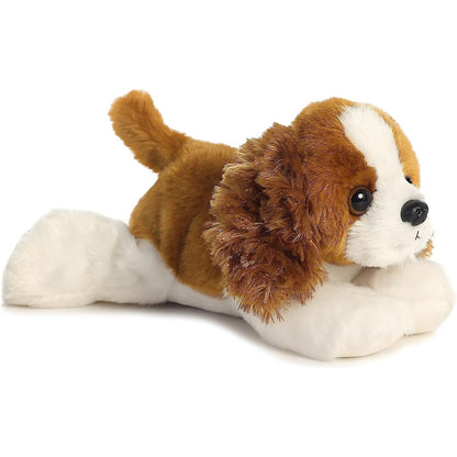 Angled front view of the 8-inch Aurora Mini Flopsie Charles the Cavalier stuffed animal lying down, showing its brown and white coat and fluffy ears.