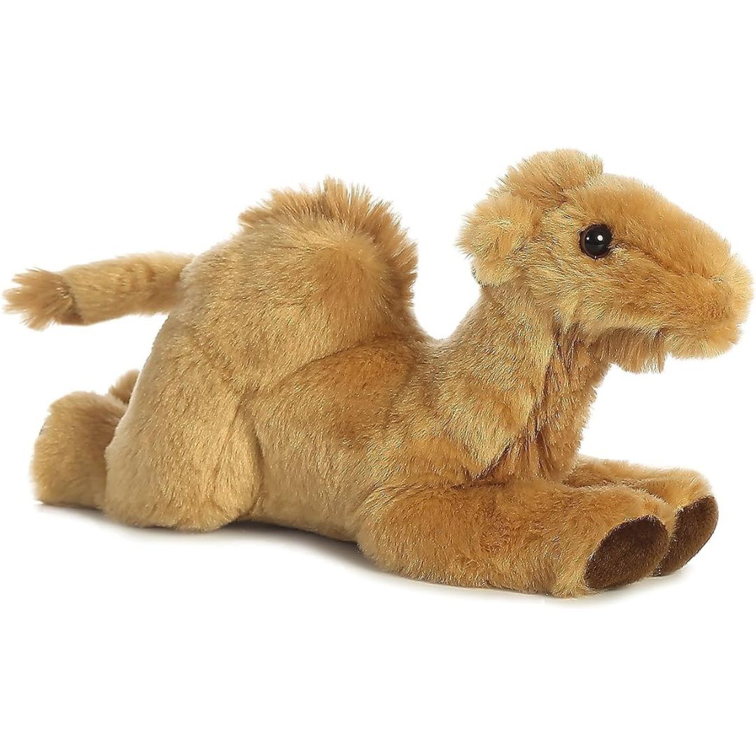 Angled side view of the Aurora Mini Flopsie Camel 8-inch plush resting on its belly, featuring soft sandy-gold fur and a fluffy single hump.