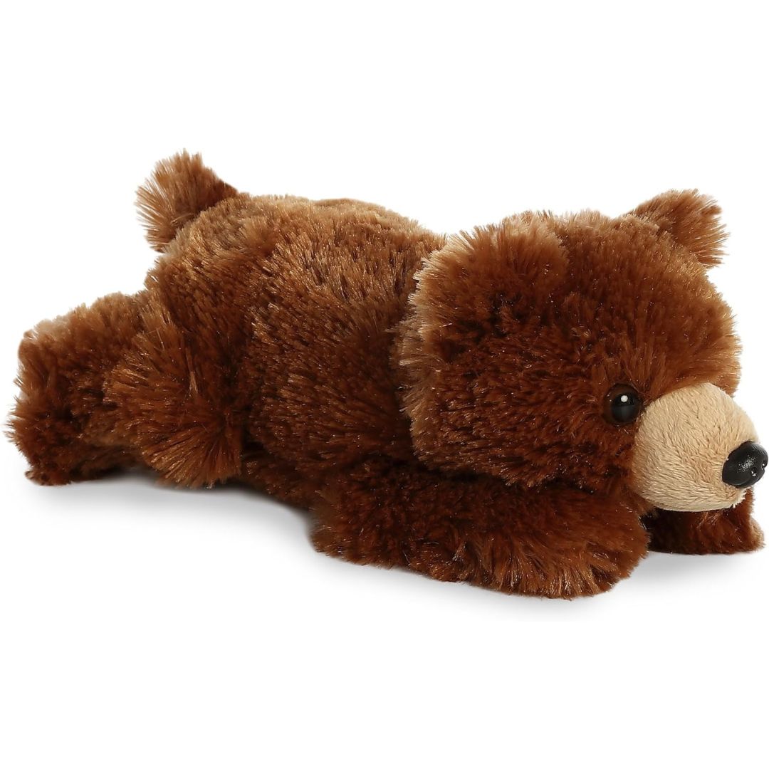Angled front view of the 8-inch Aurora Mini Flopsie Grizzly Bear stuffed animal lying down, showing its fluffy brown fur and tan snout.