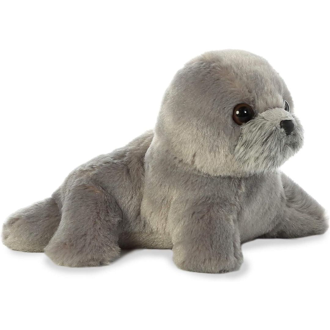 Angled front view of the 8-inch Aurora Mini Flopsie Harpo Seal stuffed animal resting on its tummy, showing its soft grey plush coat and front flippers.