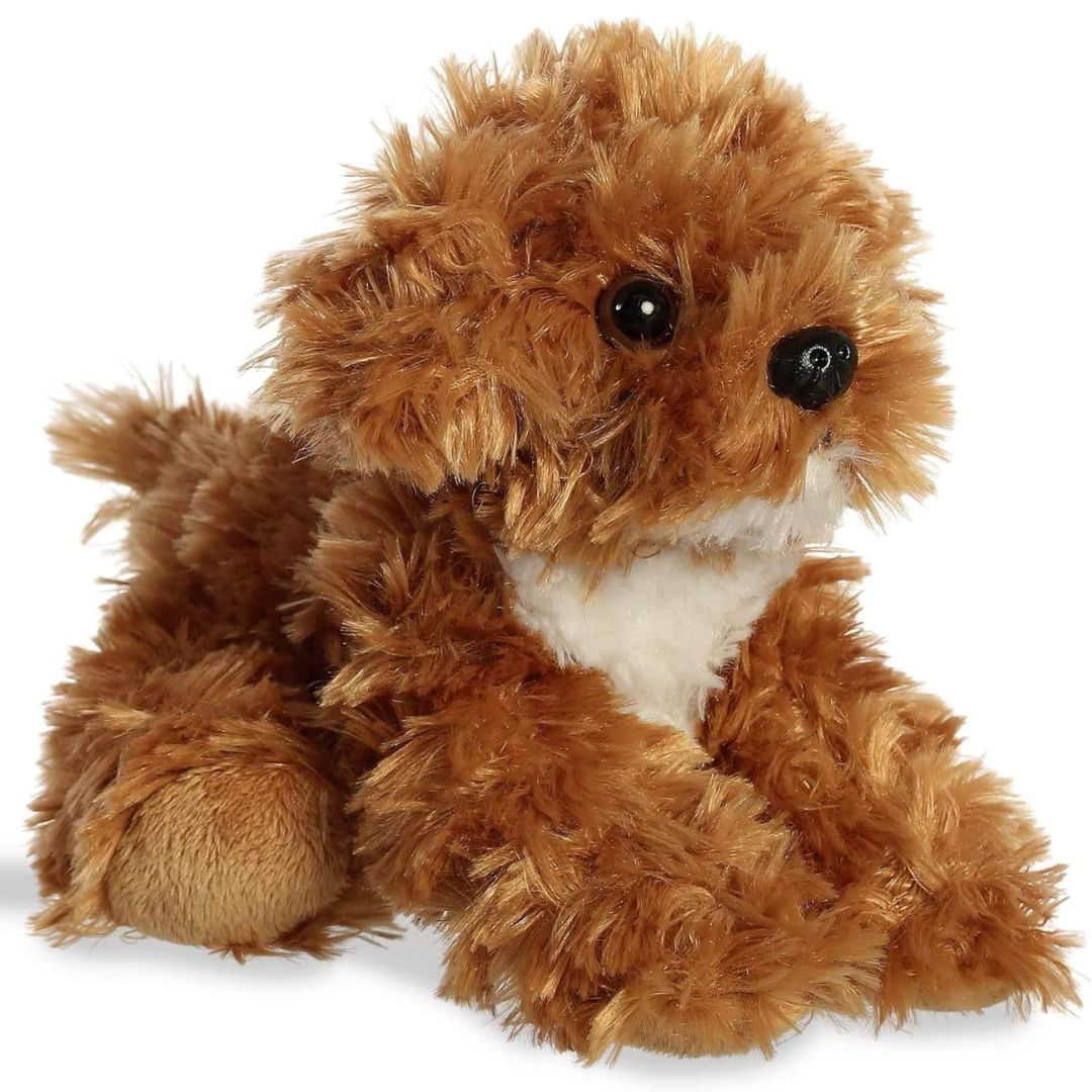 Angled front view of the 8-inch Aurora Mini Flopsie Chai Cockapoo stuffed animal lying down, showing its fluffy brown coat and white chest.