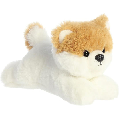 Angled view of the Aurora Mini Flopsie 8-inch Pom the Pup plush resting on its belly, showing its fluffy white and tan fur.