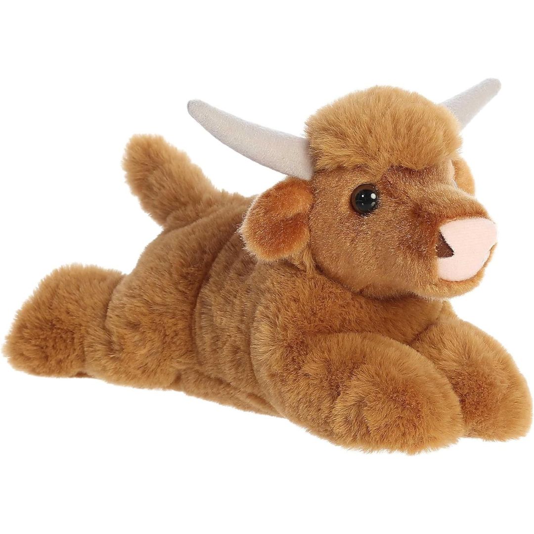 Angled front view of the 8-inch Aurora Mini Flopsie Highland Cow stuffed animal resting on its tummy, showing its shaggy brown coat and curved horns.