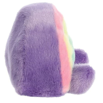 Side profile view of the Palm Pals Rainbow plush toy highlighting its bean-weighted sitting posture and soft purple back.
